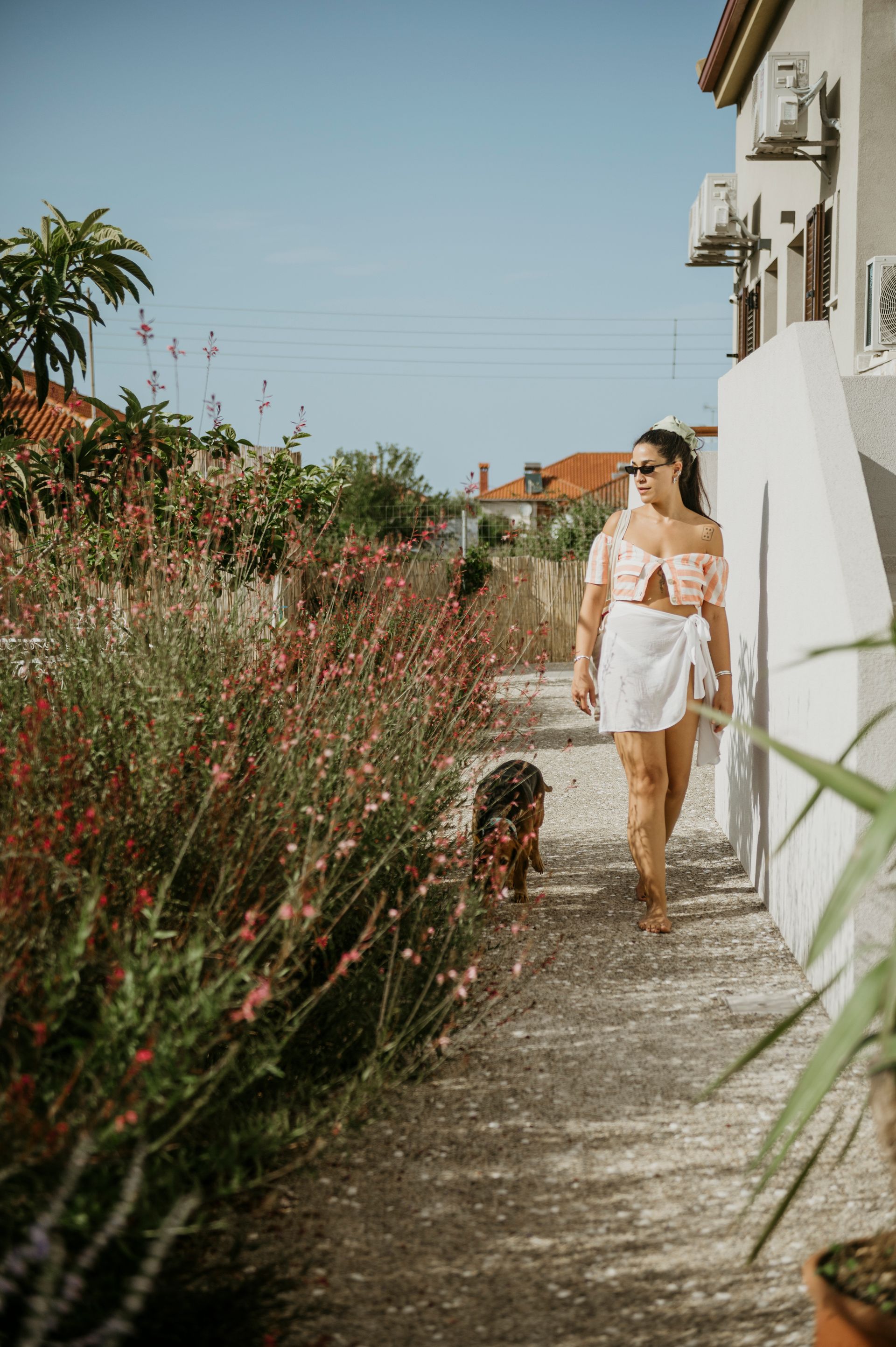 A woman is walking her dog down a sidewalk.