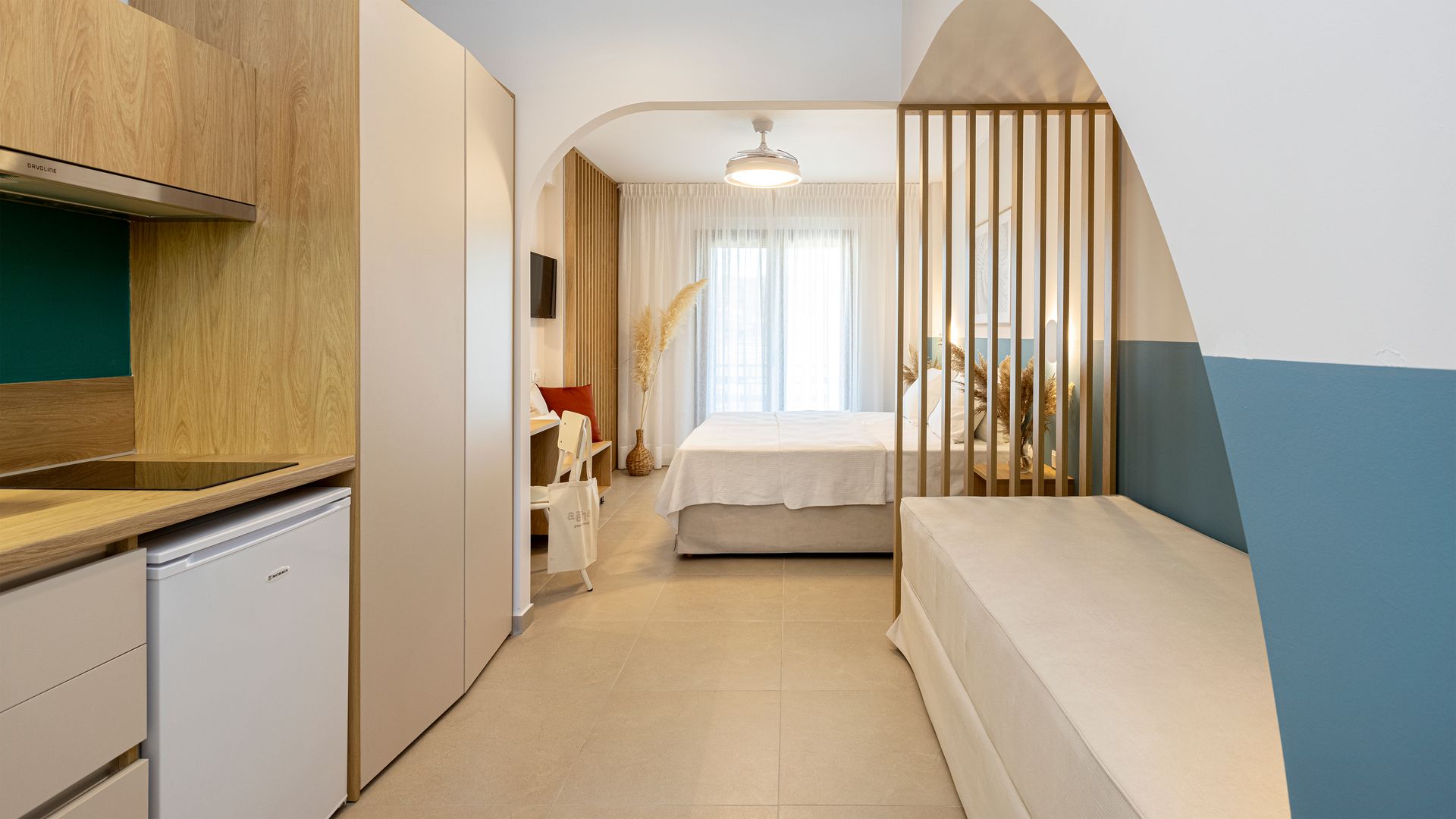 A bedroom with a bed and a kitchen in a small apartment.