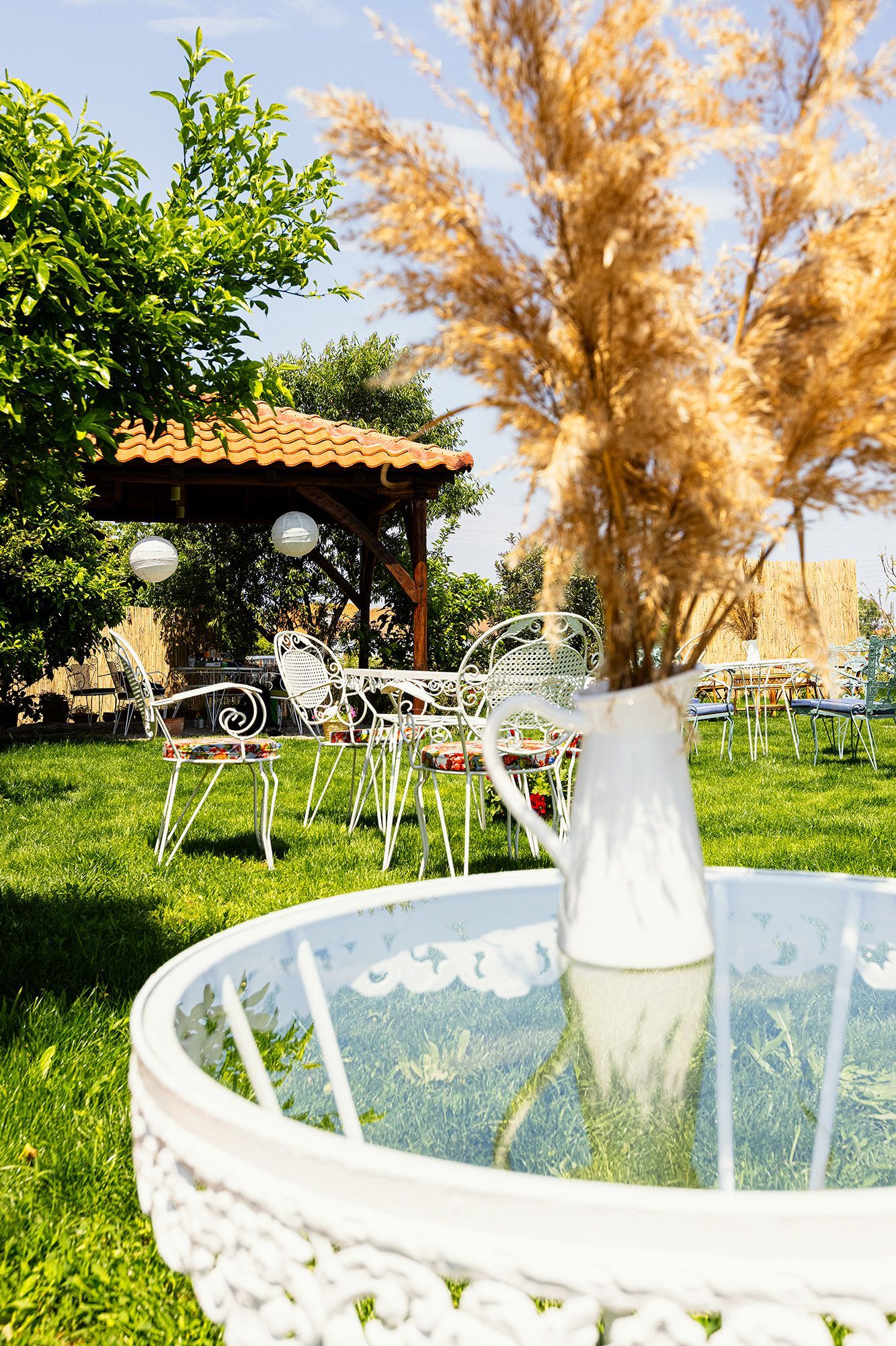 A vase of flowers is sitting on top of a glass table in a garden.