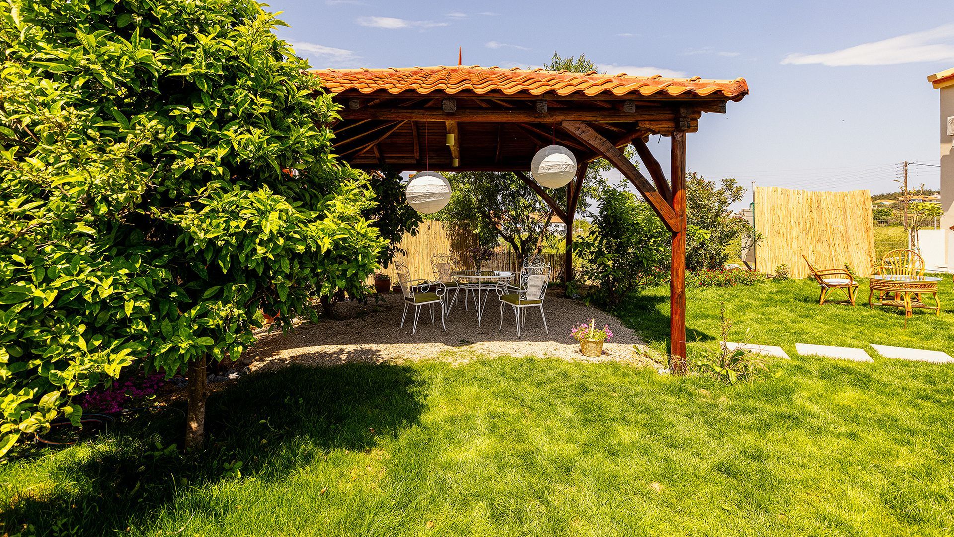There is a wooden gazebo in the middle of a lush green garden.