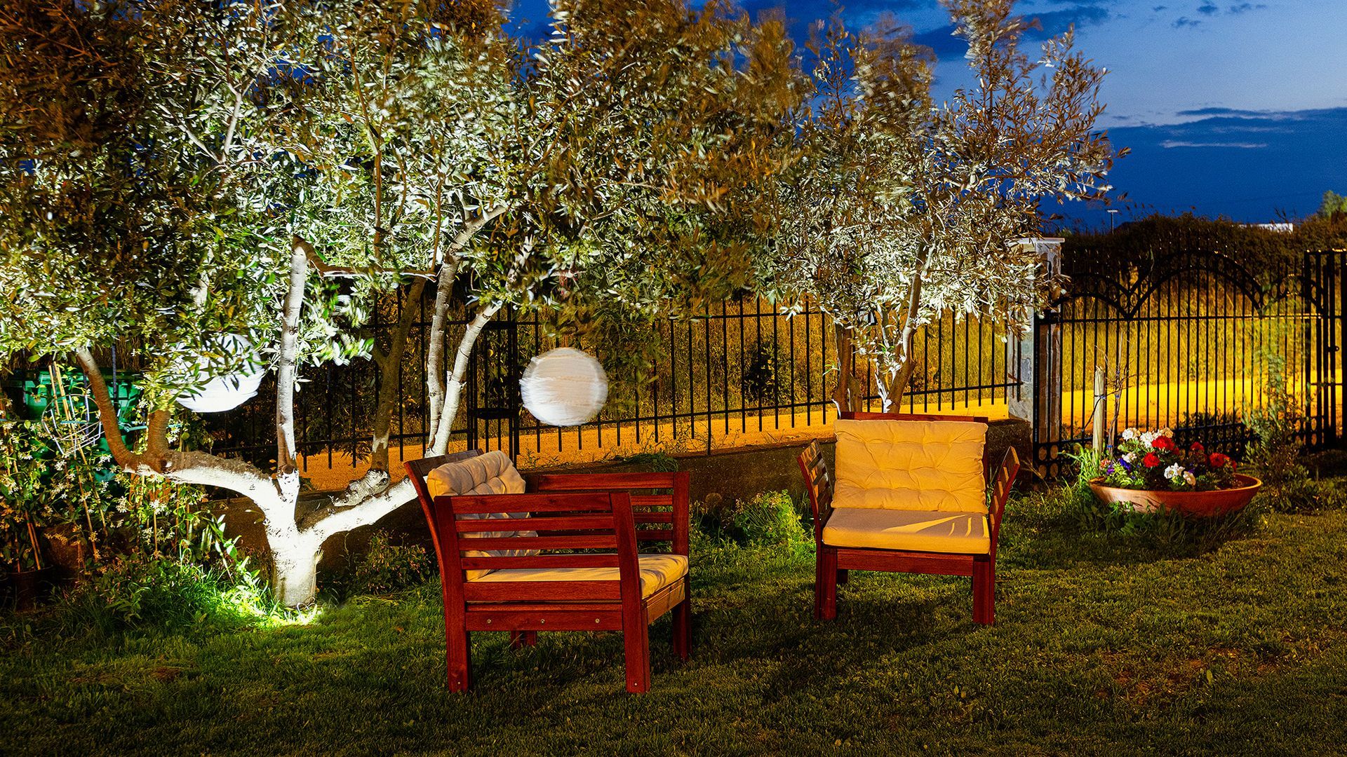 A wooden bench and chairs in a backyard at night.