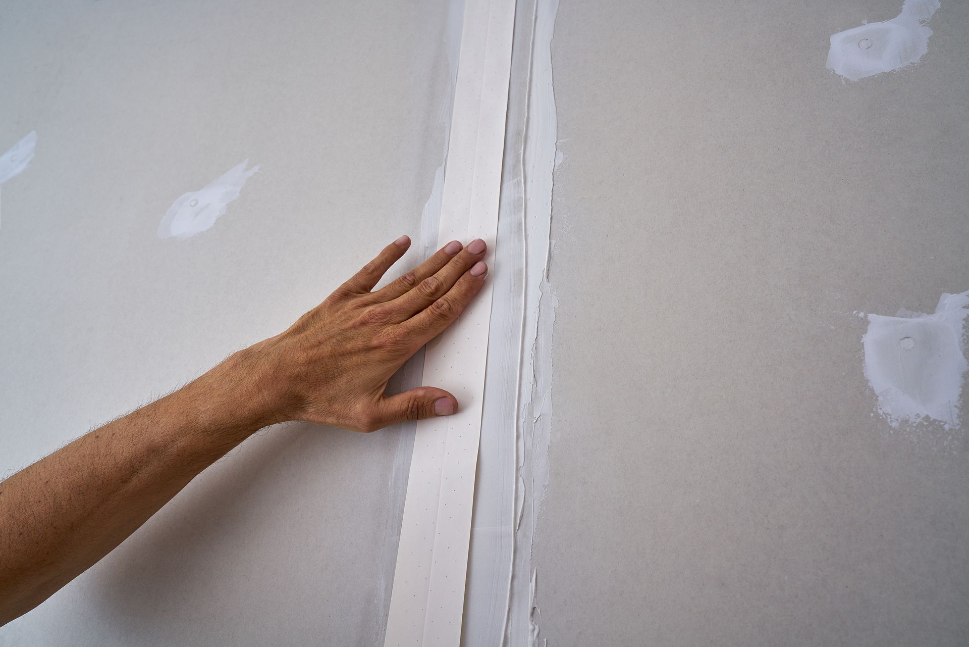 A person is touching a piece of drywall on a wall.