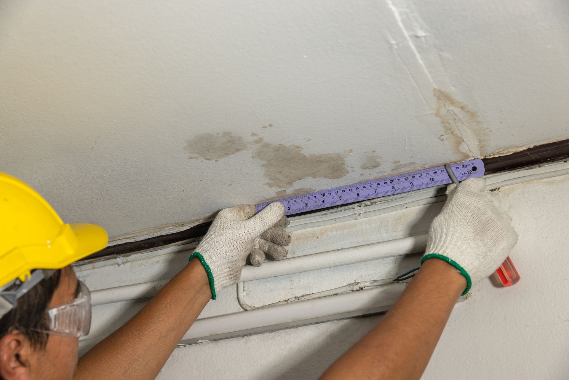 A man is measuring a wall with a ruler.