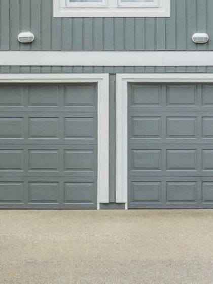 There are two garage doors on the side of a house.