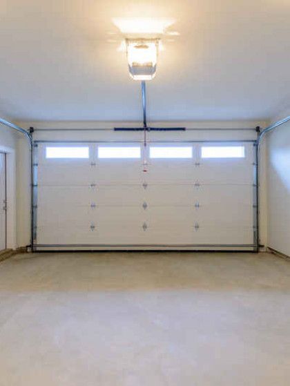 An empty garage with a garage door open and a light on the ceiling.