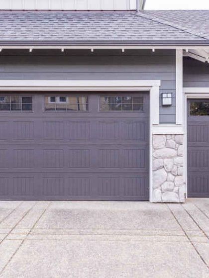 A house with a purple garage door and a stone wall.