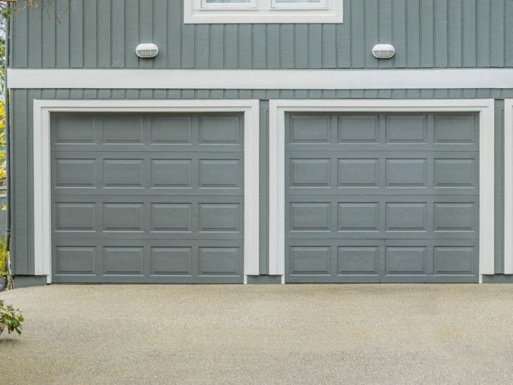 There are two garage doors on the side of a house.