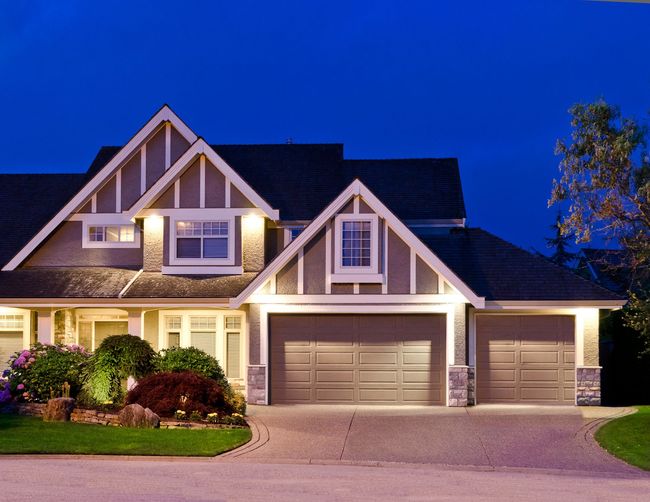 A house with two garage doors is lit up at night