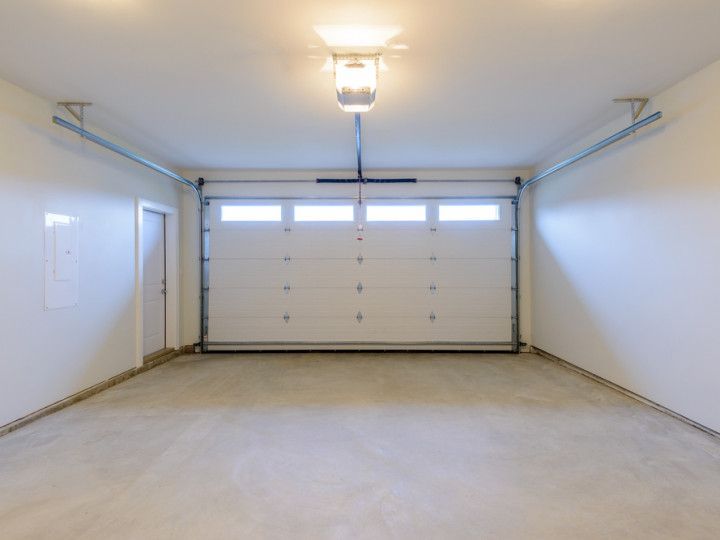 An empty garage with a garage door open and a light on the ceiling.