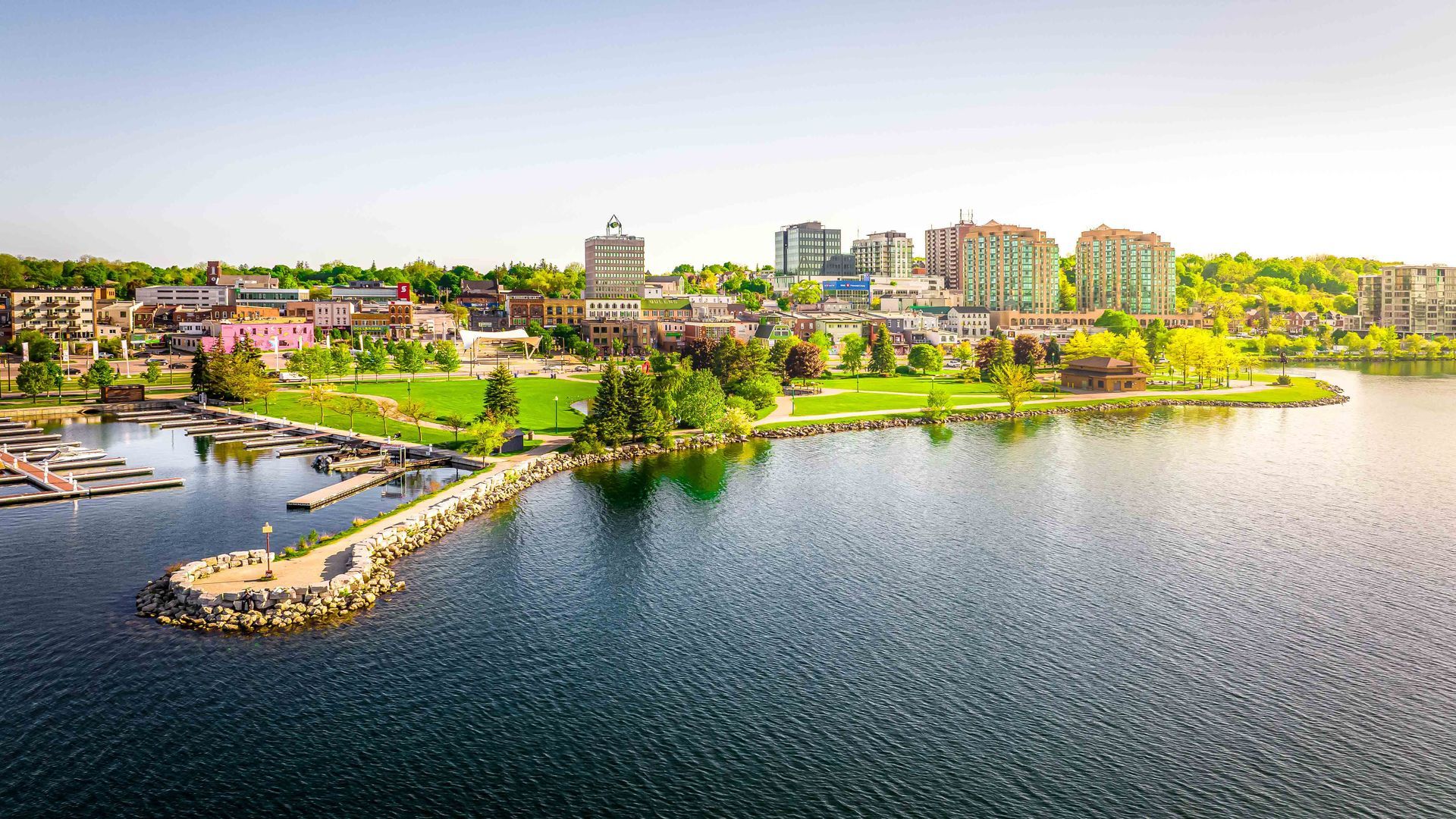 a drone photo of the city of Barrie. Green park along lakeshore with clear blue skies and city skyline in the background