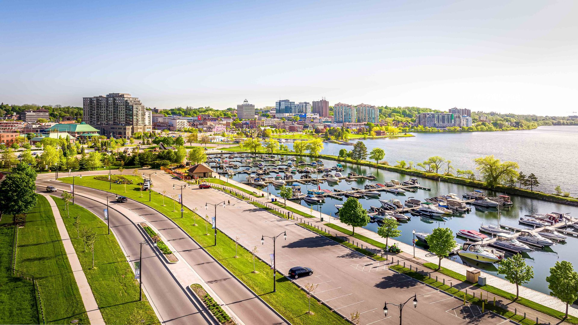 city skyline in background from a drone, greenery in the foreground, with boats parked at a marina