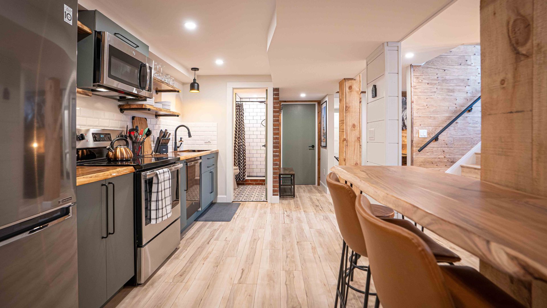 the kitchen, appliances, fridge, stove, and stairs coming into the unit, wooden rectangular dining table and high chairs
