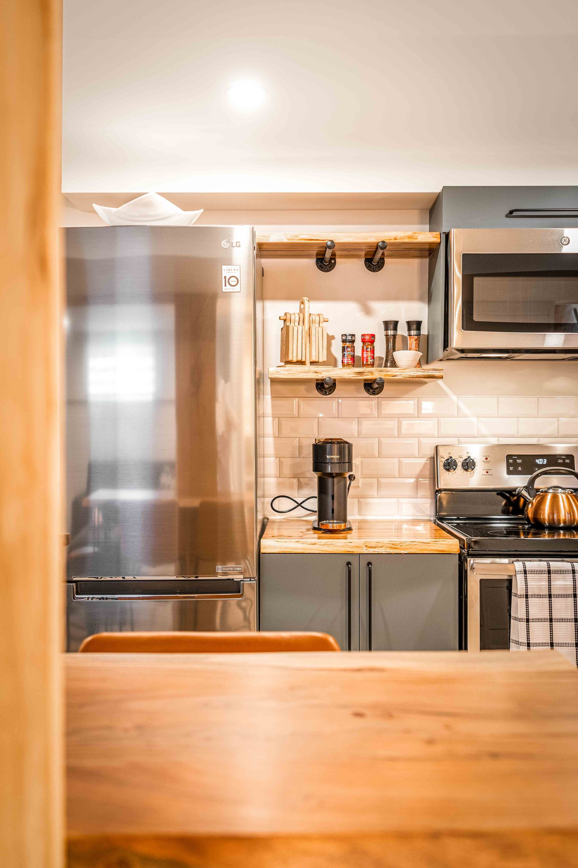 light green kitchen cabinets, stainless steel fridge, microwave and oven, coffee maker on wooden kitchen counter top
