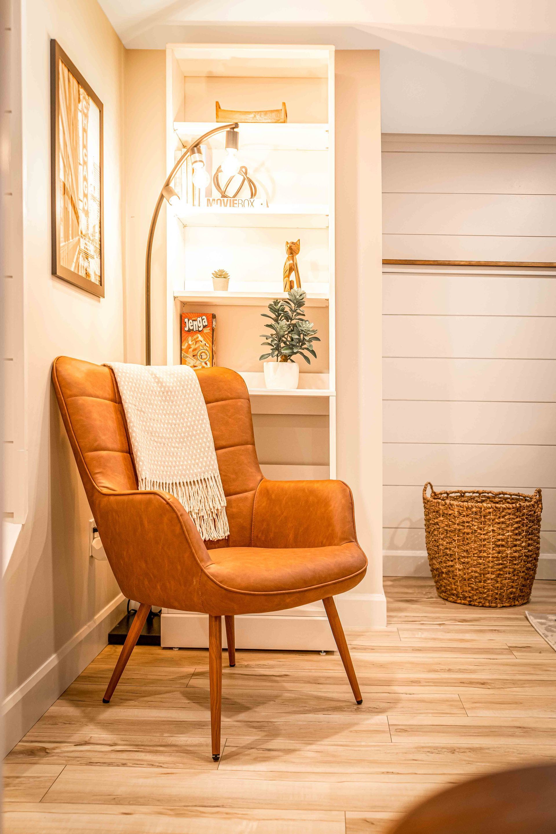 reading nook, brown leather chair, floor lamp above chair with warm yellow glow, book shelf, with books in background