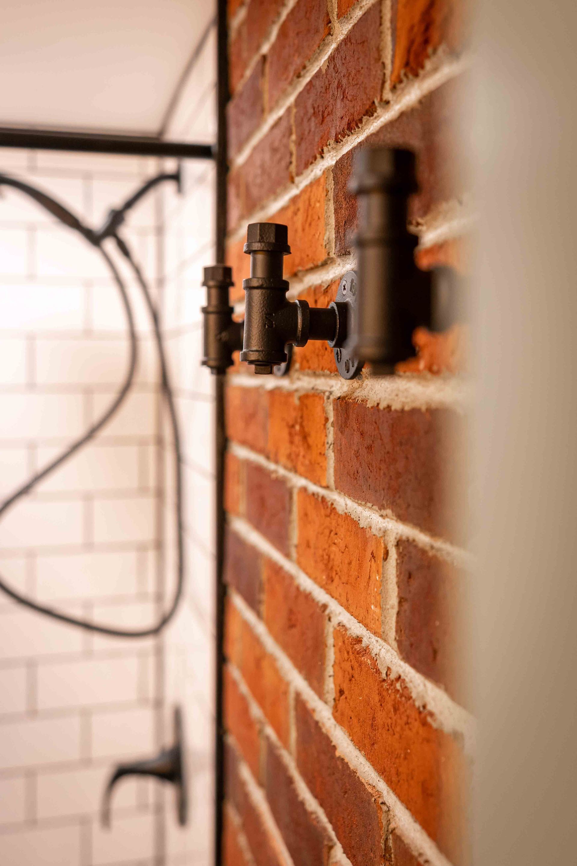 red brick wall in bathroom with industrial style pipe bath towel hooks