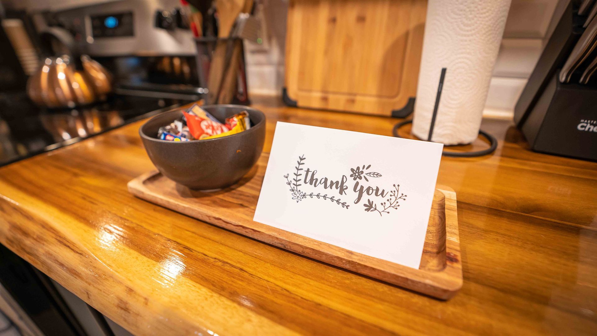 a thank you card with a bowl of candies on top of a wooden kitchen counter top

