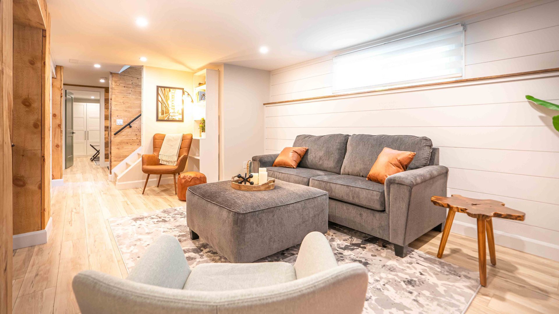 cozy living room with grey couch and ottoman, brown reading chair
