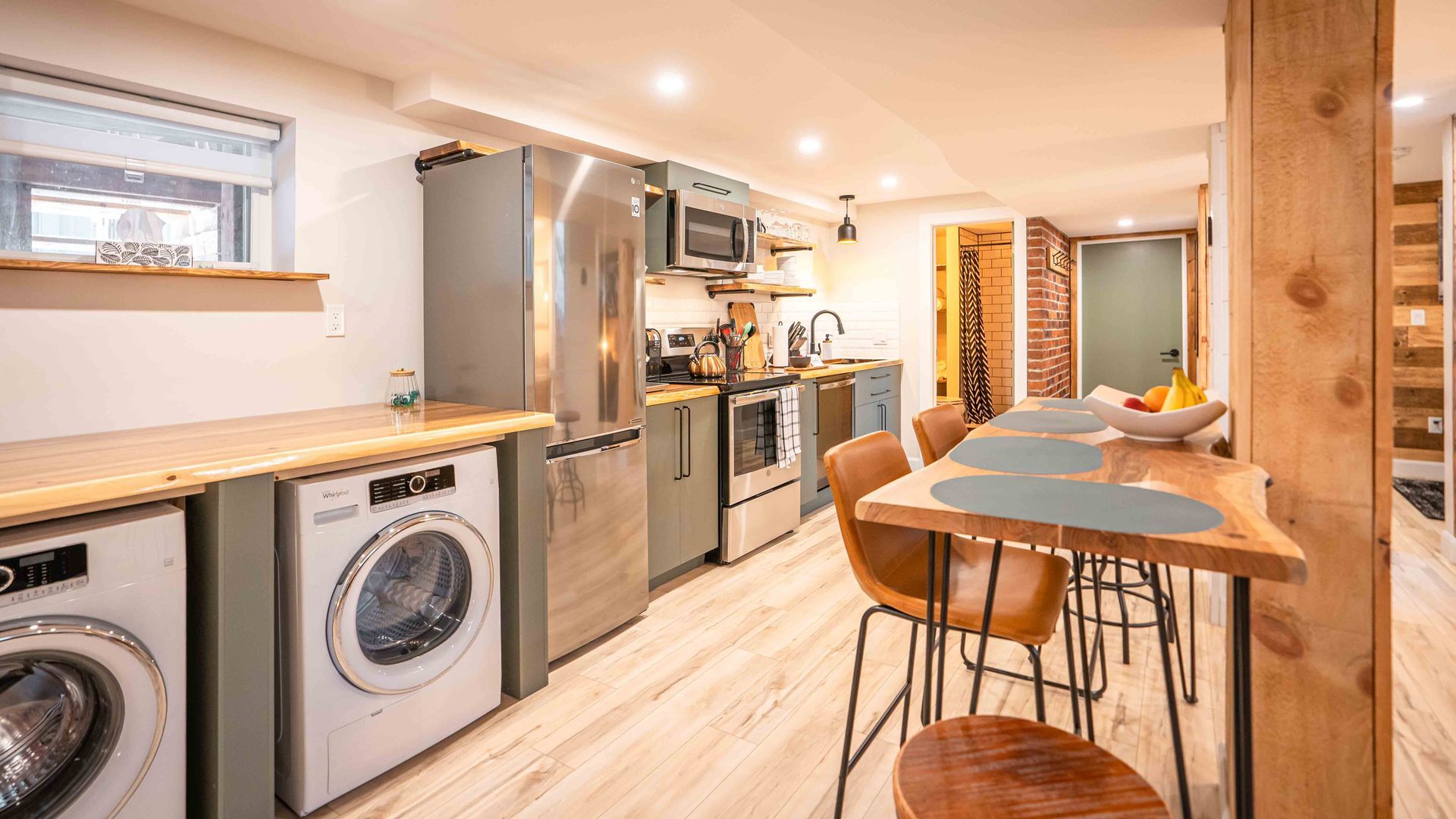 kitchen with light green cabinets, wooden dining table and laundry machines with a wooden counter top above