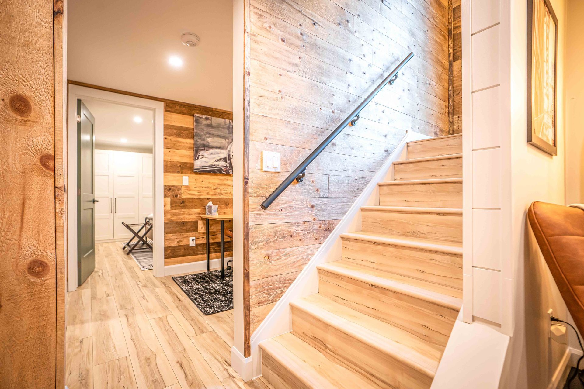 bright light brown staircase coming into the unit with wooden barn board style walls