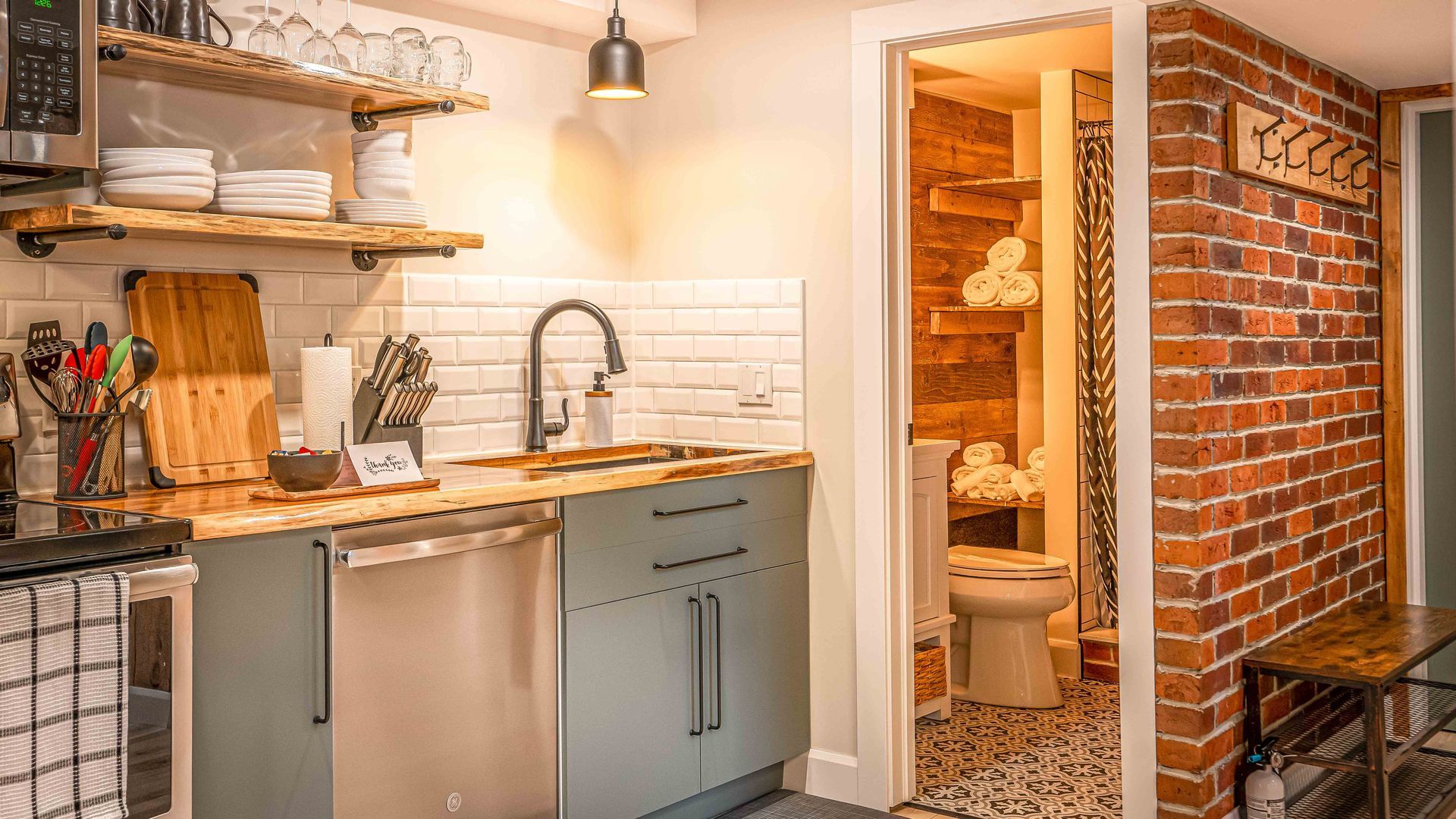 stainless steel dishwasher in a kitchen with wooden countertop and subway tile as backsplash, red brick accent wall