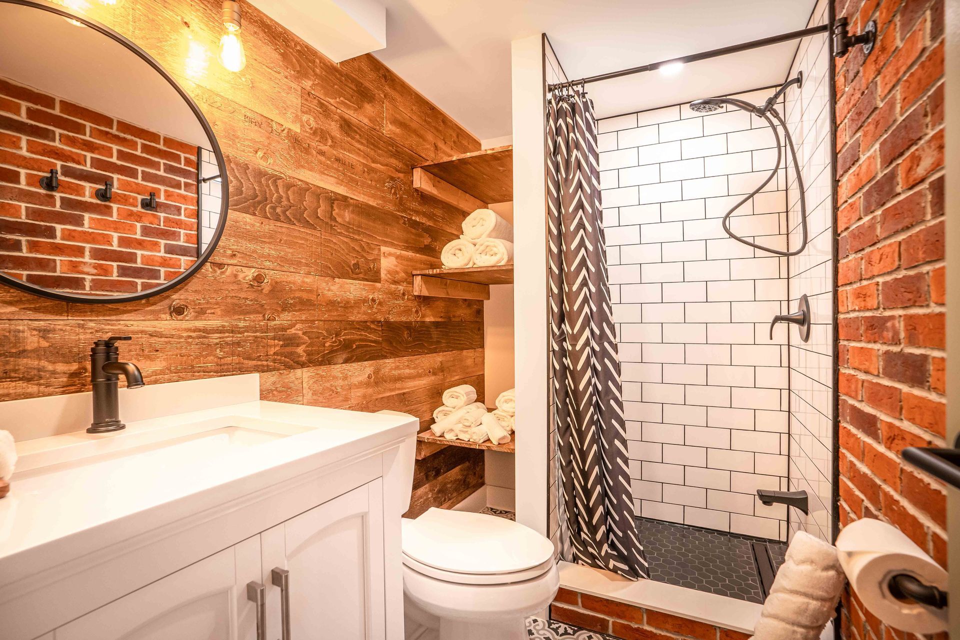 rustic bathroom with subway tile shower, barn board wooden wall, red brick accent wall with white vanity