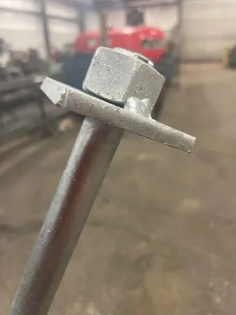 A close up of a metal pole with a nut on it.
