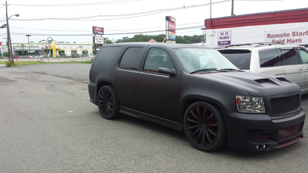 A black suv is parked in a parking lot in front of a recycle store
