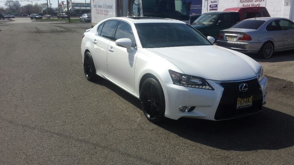 A white lexus is parked on the side of the road.