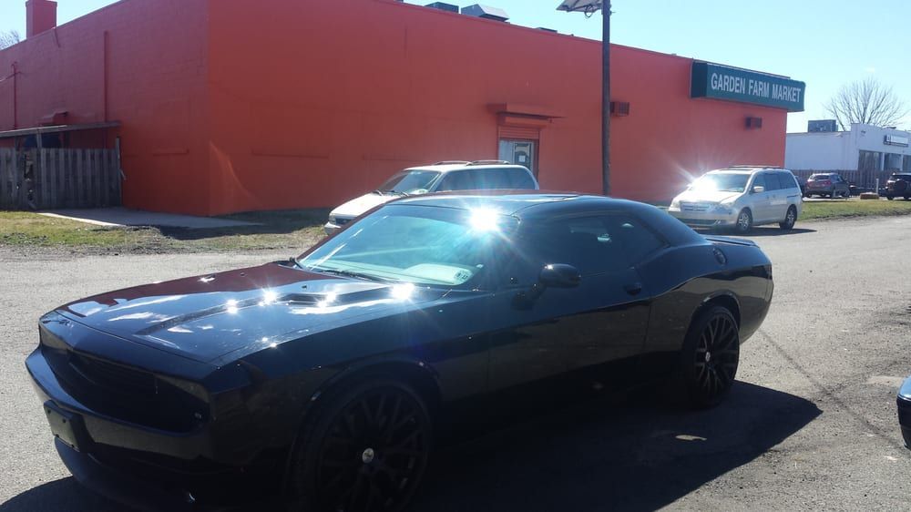 A black dodge challenger is parked in front of an orange building.