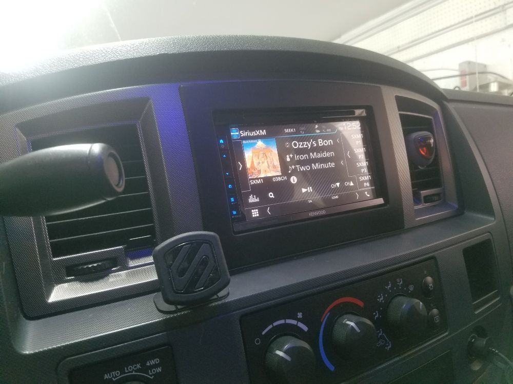 A car dashboard with a radio and a phone holder.