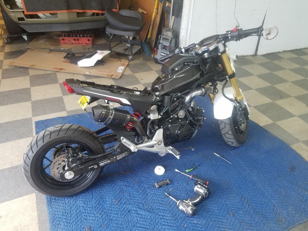 A motorcycle is sitting on a blue mat in a garage.