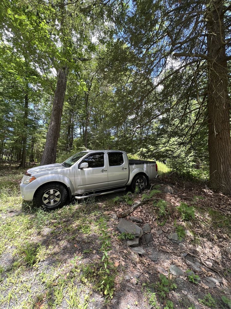 A white truck is parked in the middle of a forest.