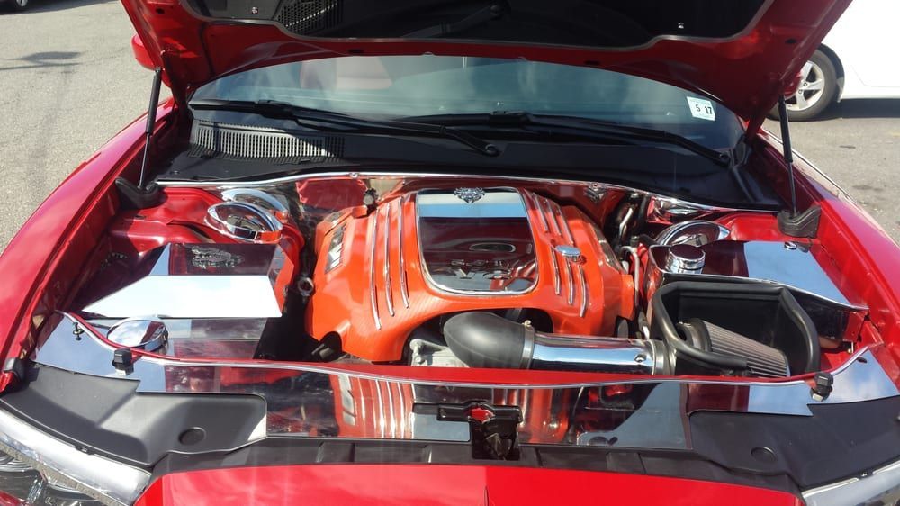 A red car with the hood up and the engine exposed
