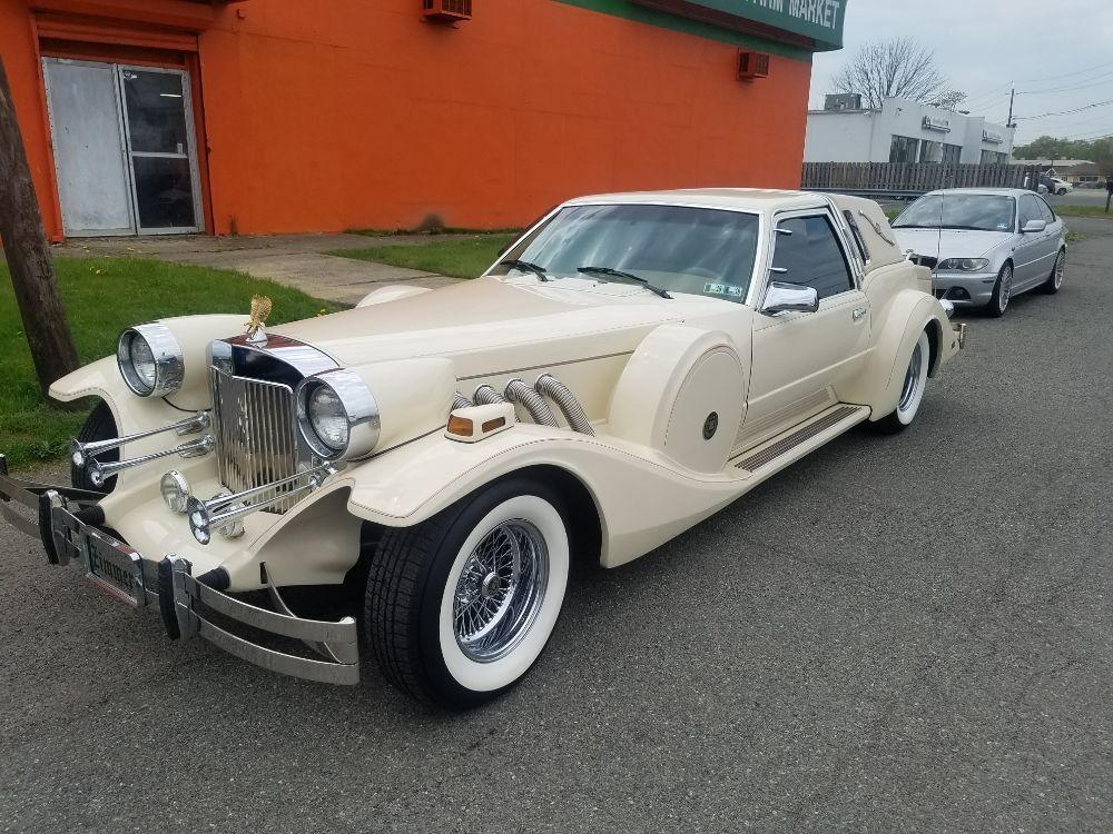 A white car is parked in front of an orange building.