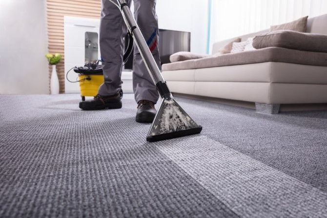 Person vacuuming a gray carpet in a modern living room