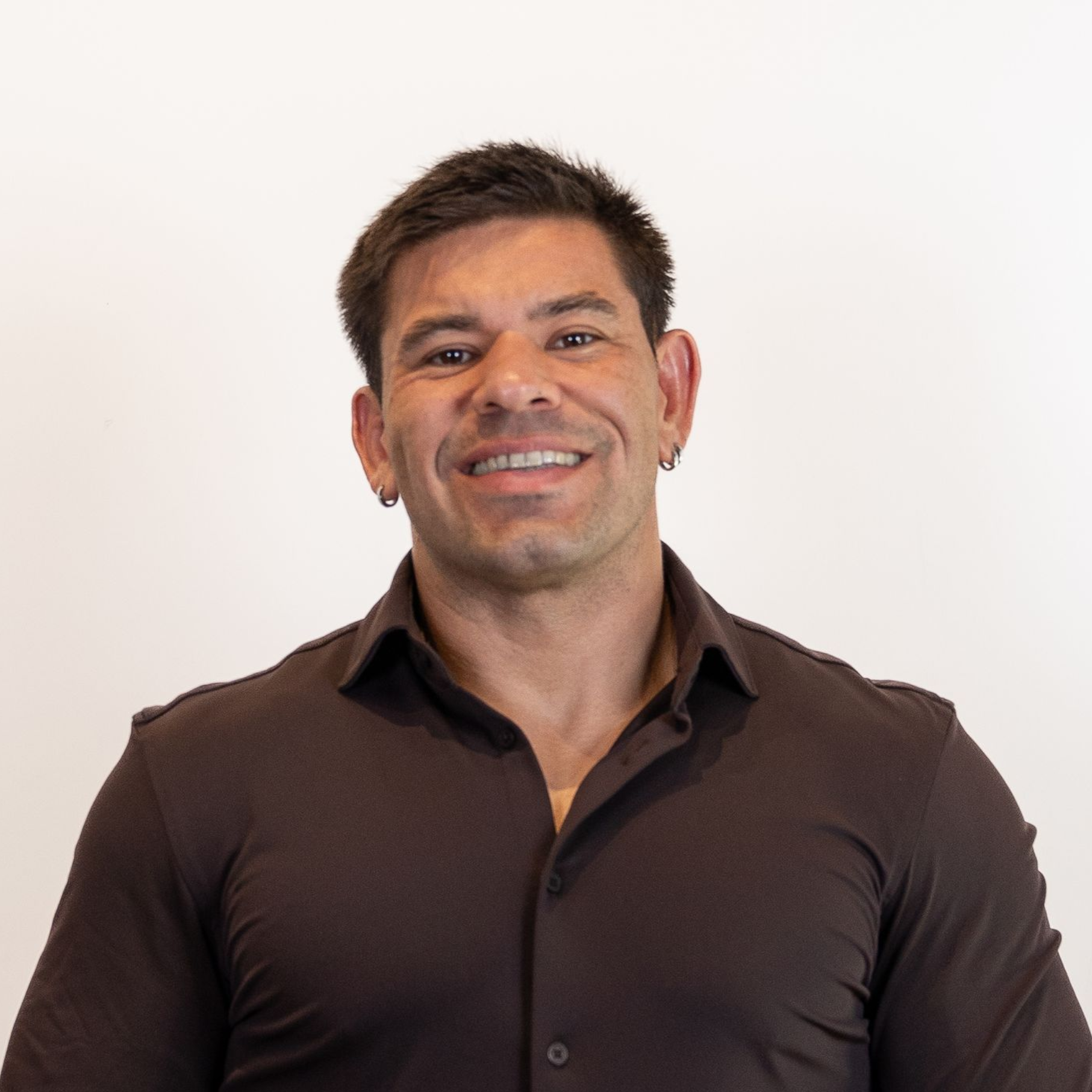 Smiling man in a dark brown shirt against a plain white background