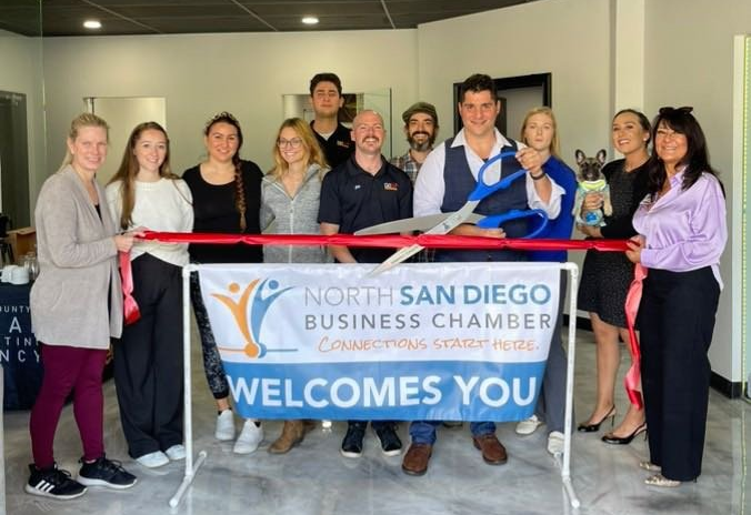 A group of people are standing around a sign that says welcomes you.