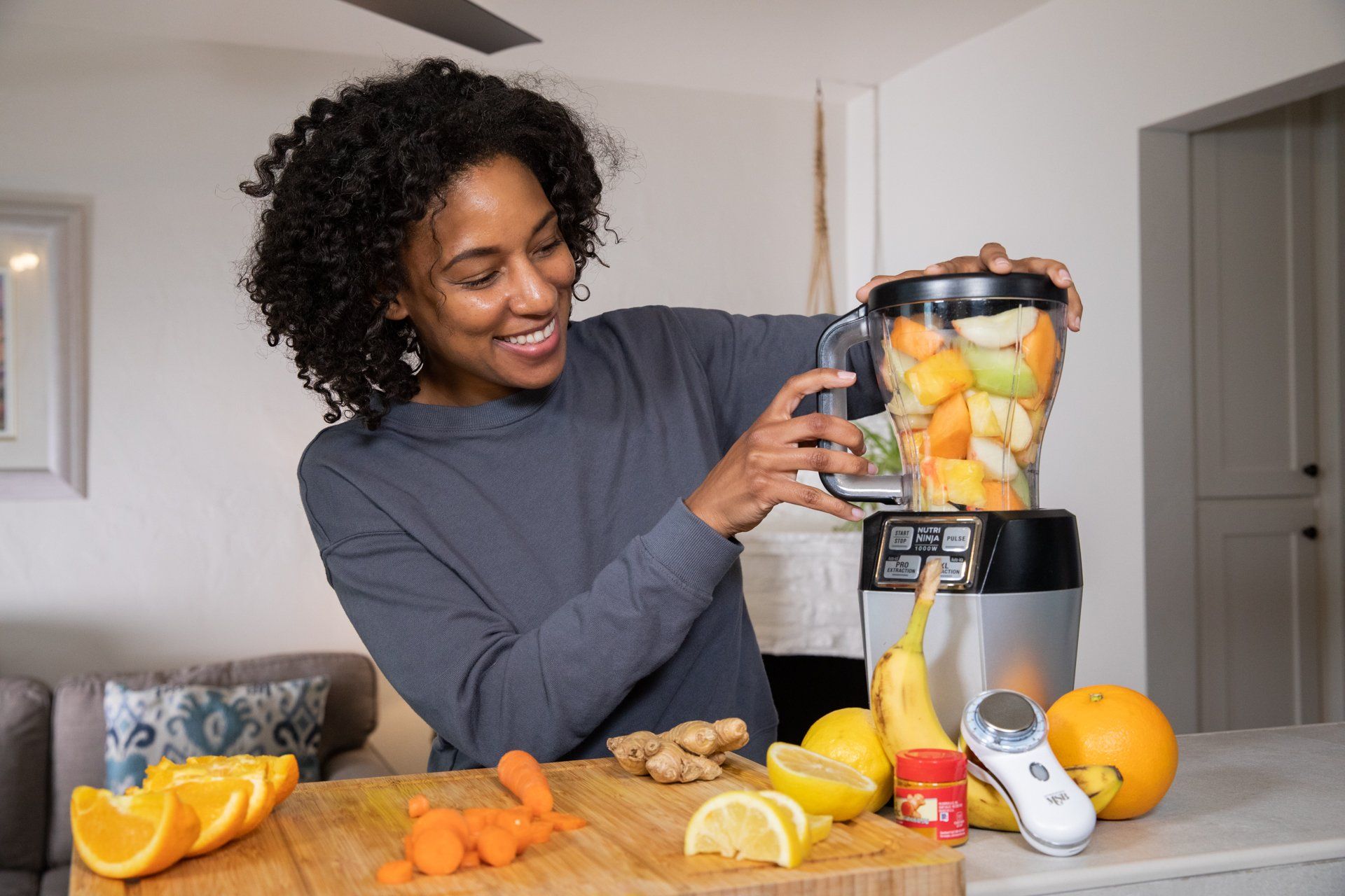 A woman is making a smoothie in a blender