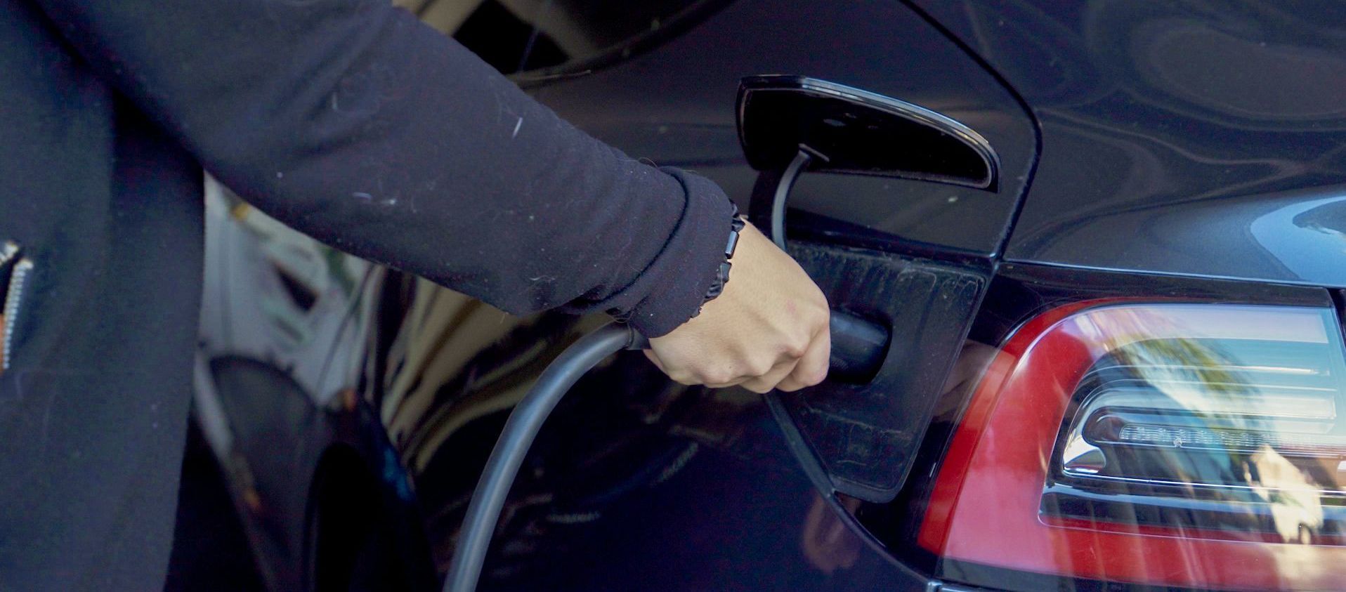 A person is charging an electric car with a charger.