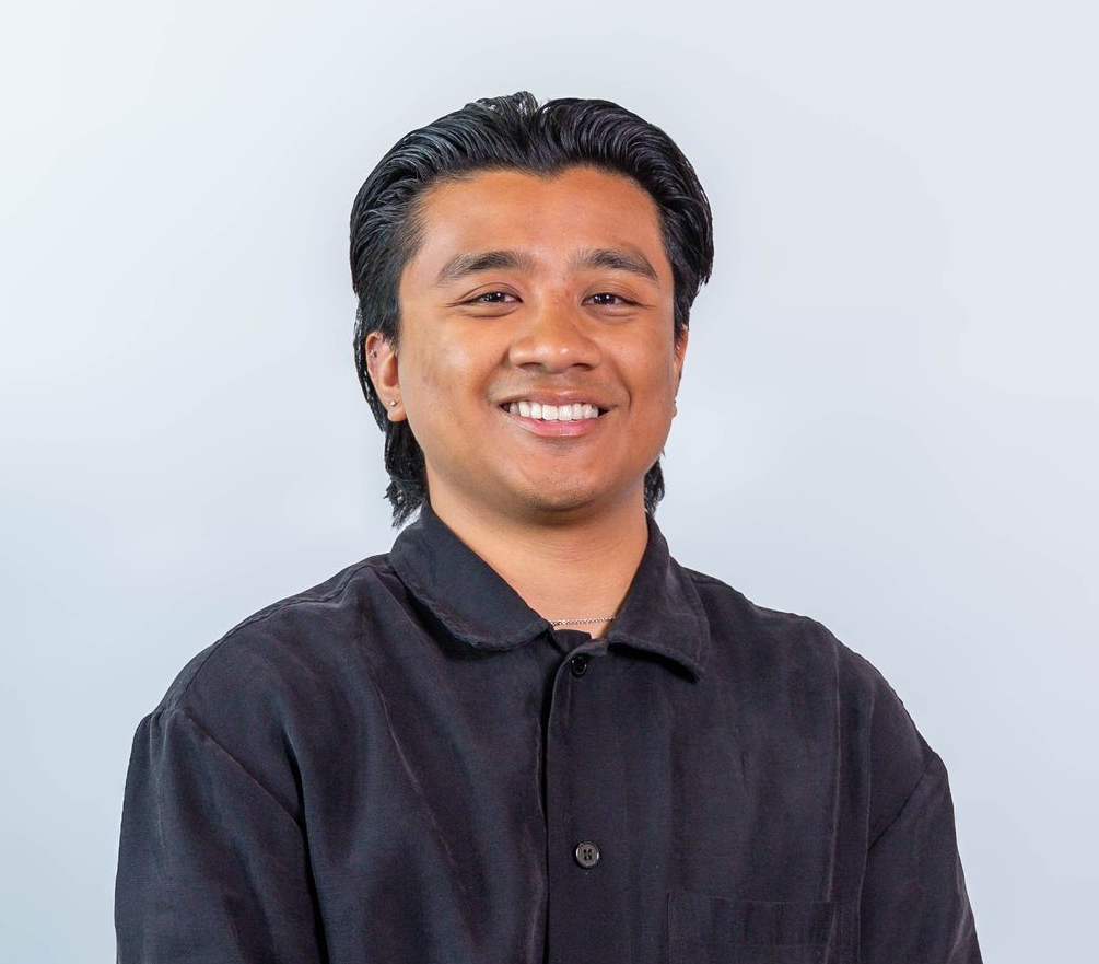 Smiling person in a dark shirt against a light gray background