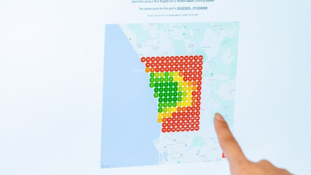 A person is pointing at a map on a computer screen