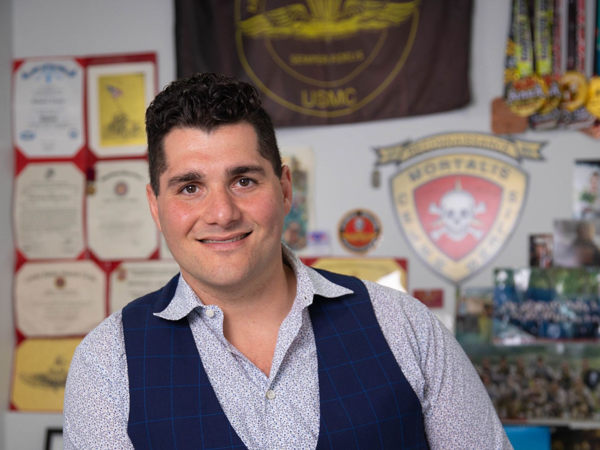 A man stands in front of a usmc flag
