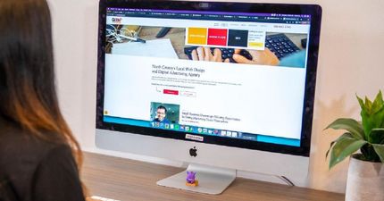 A woman is sitting in front of an apple computer