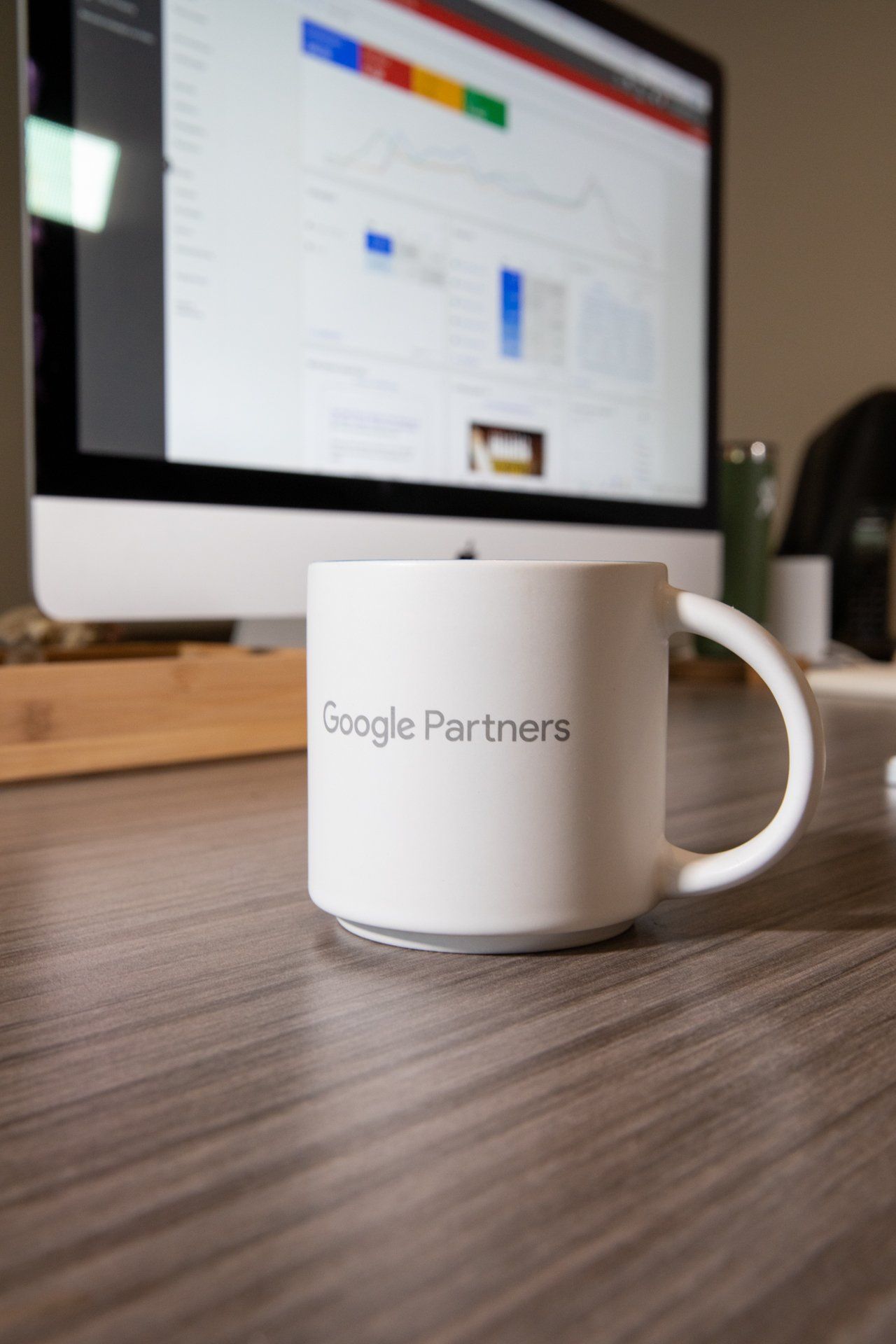 A coffee mug that says google partners sits on a desk in front of a computer monitor