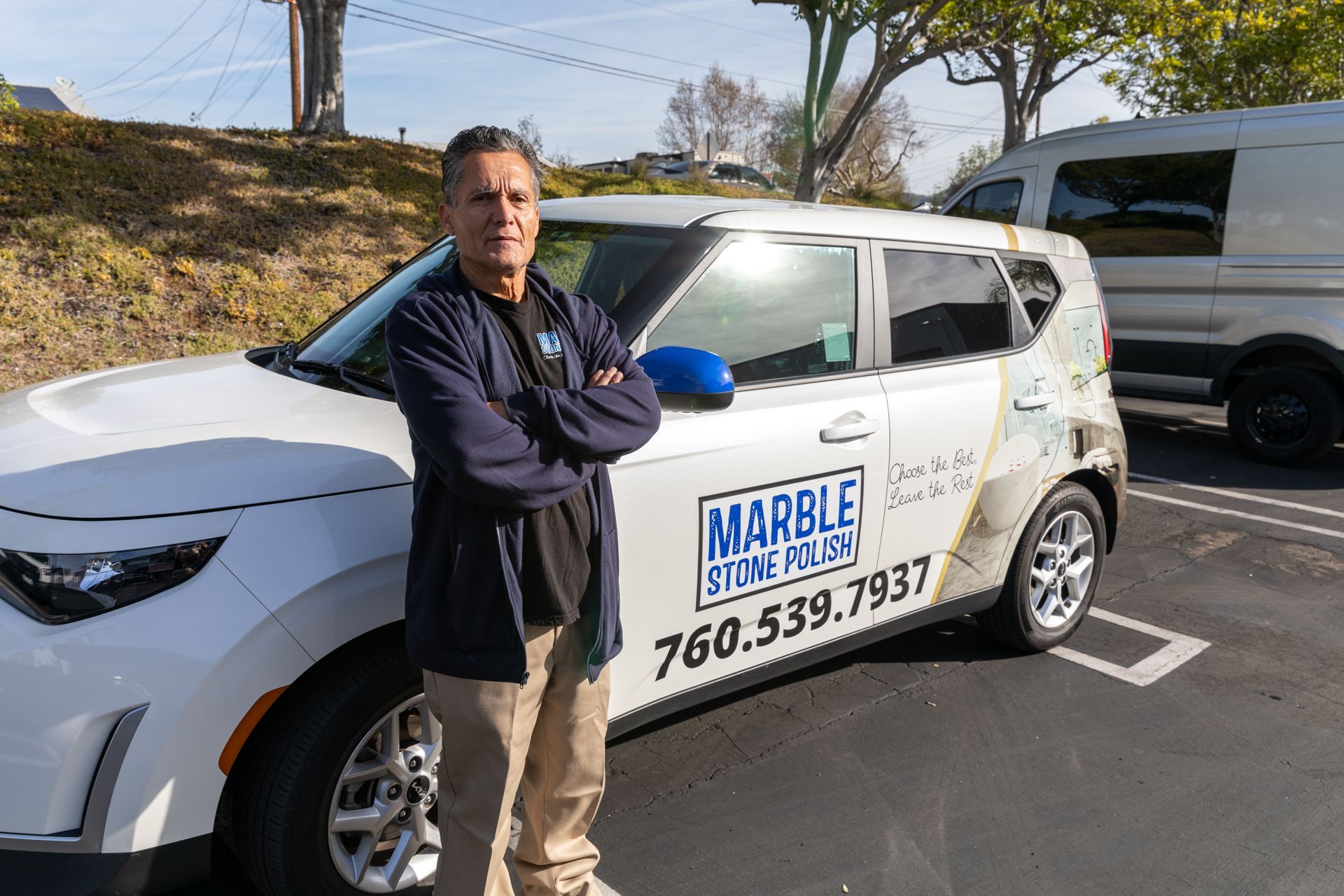 A man stands in front of a marble silver car