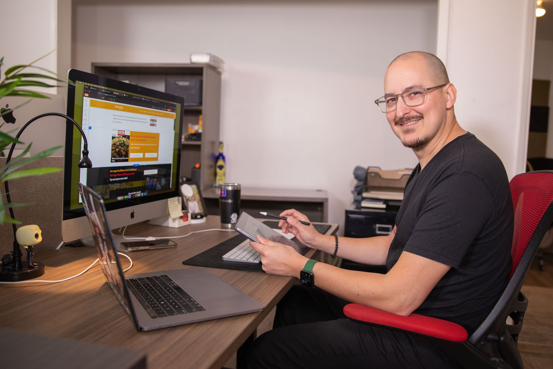 A man is sitting at a desk with a laptop and a computer