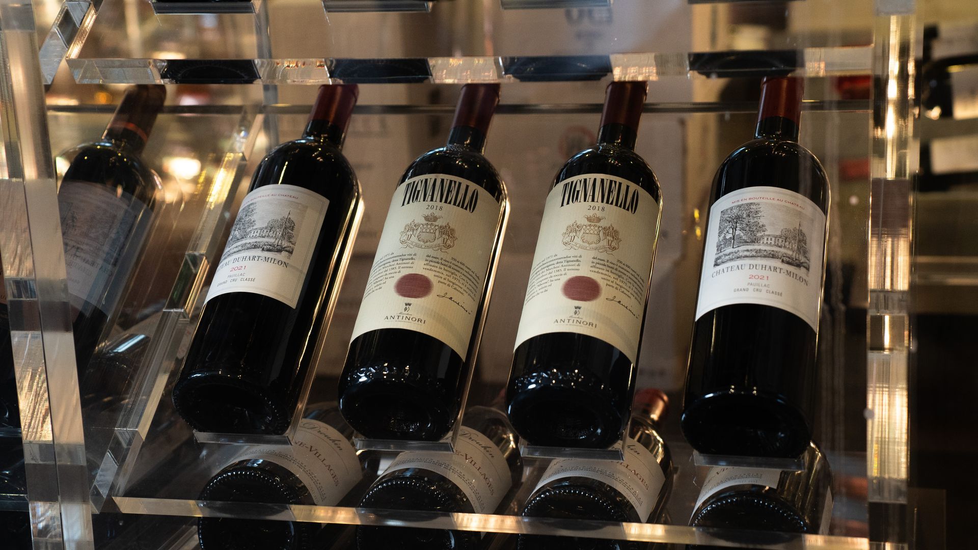 Vinflasker udstillet i en vindispenser. Rødvinsflasker er vinklede og mærket med vindetaljer.