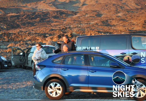 Guests and cars beside the Night Skies Tenerife coach in volcanic scenery