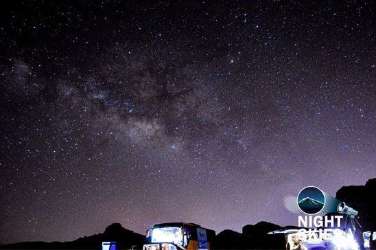 Milky Way above the volcanic landscape and tour vehicles in Tenerife