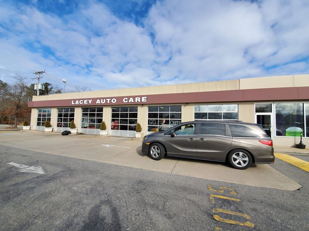 Auto shop storefront with a parked gray station wagon under a cloudy blue sky | Lacey Auto Care